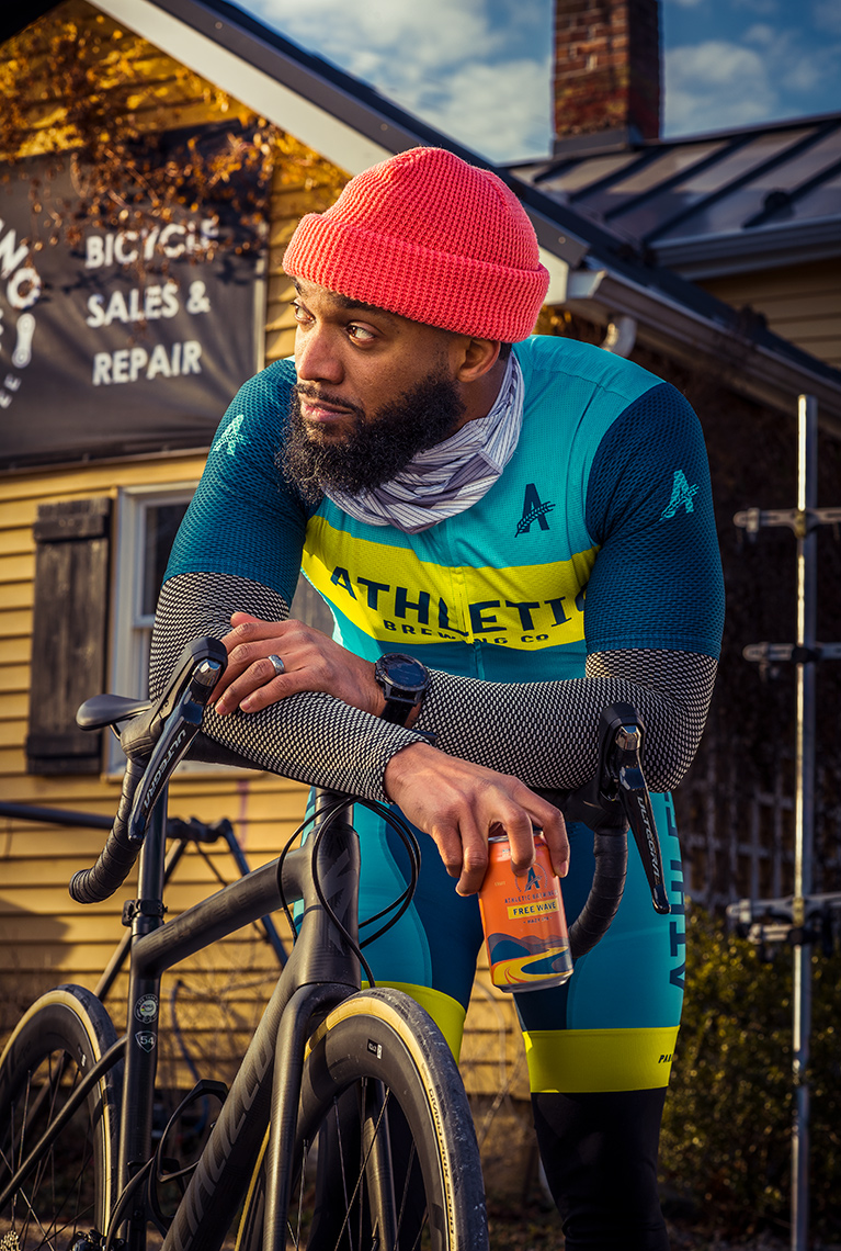 Cyclist Anthony Cooper-Jenkins holds can of Athletic Brewing Free Wave non-alcoholic beer 