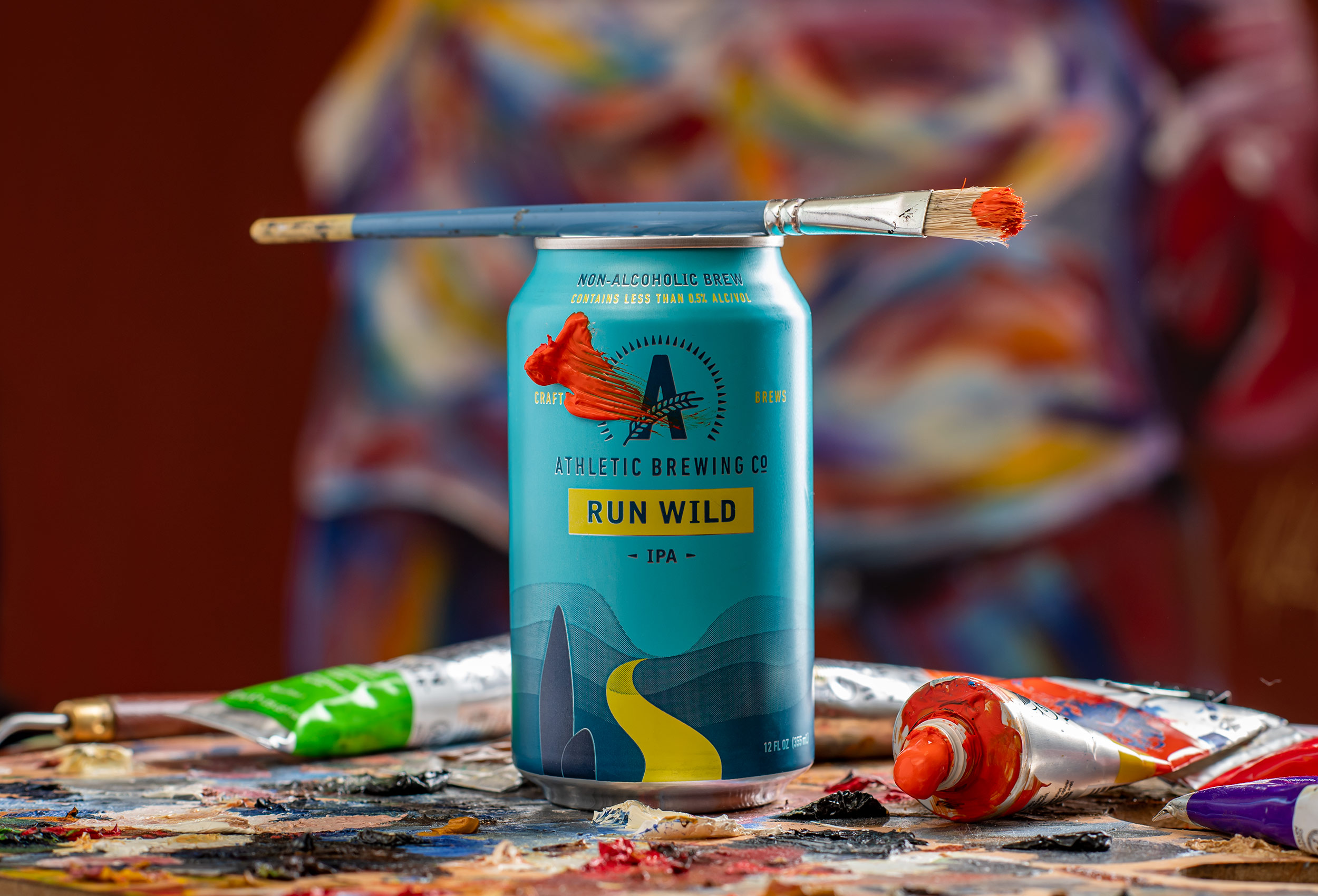 Can of Run Wild non-alcoholic beer in artist studio with paint and paint brush  product photography for Athletic Brewing Co. 