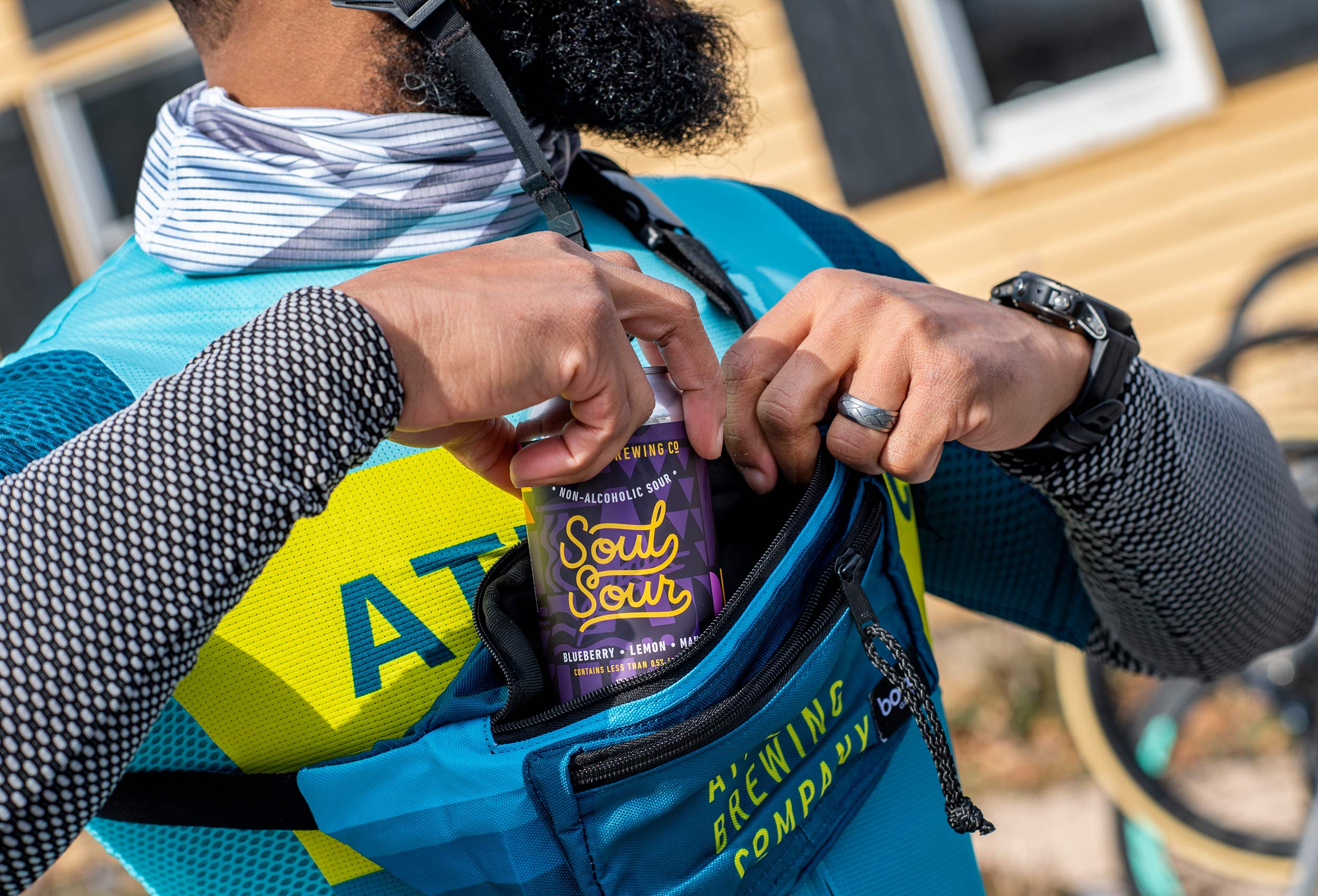 Cyclist puts can of Soul Sour into bike pouch - advertising for Athletic Brewing Co.