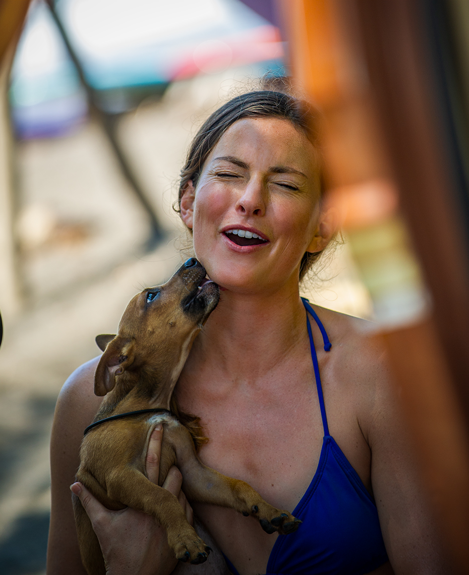 Surfer girl holds stray dog in Costa Rica - lifestyle  photography for Coppertone Sport