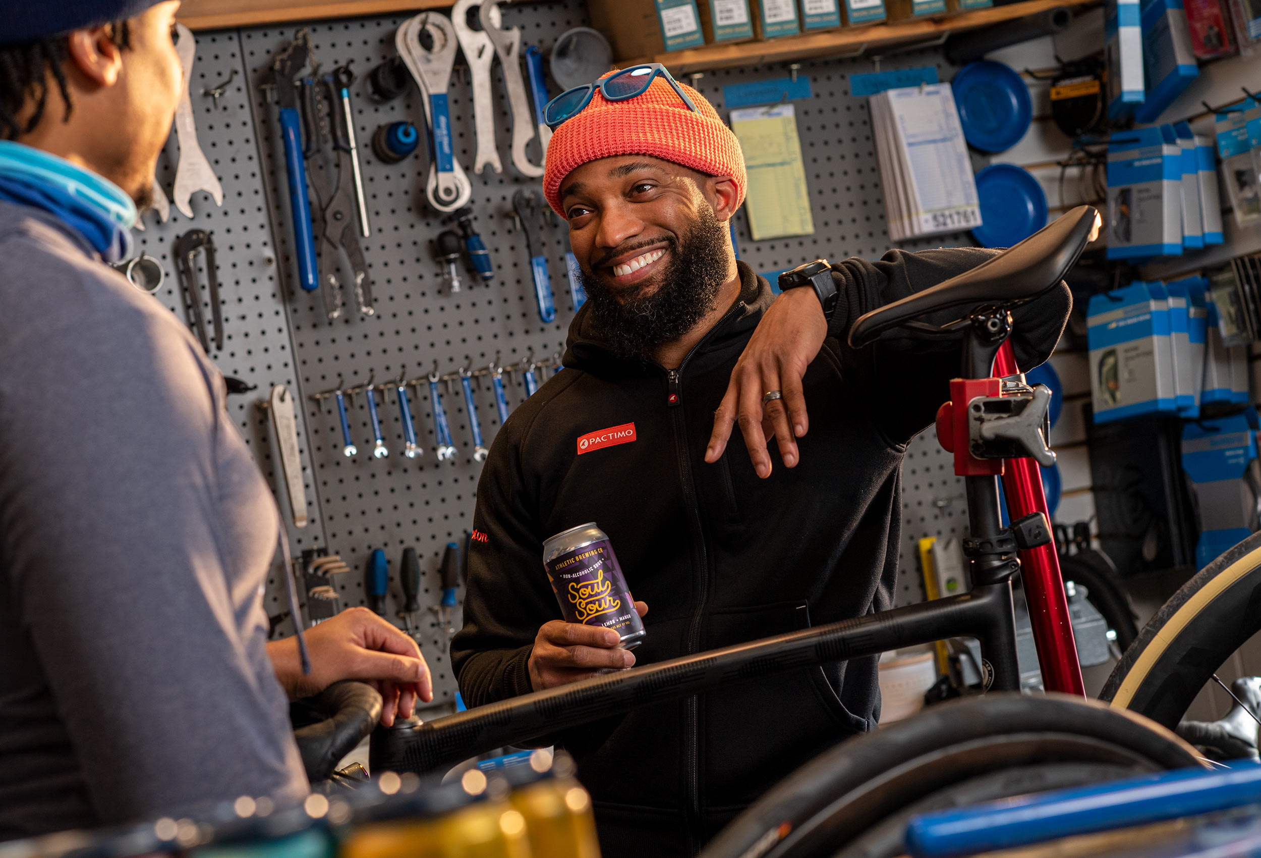 Athletic Brewing Ambassador Anthony Cooper-Jenkins holds can of Soul Sour non-alcholic beer in bike shop 