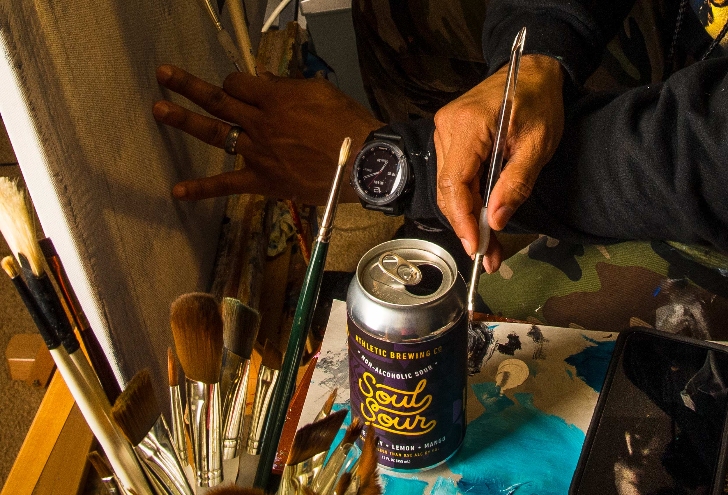 Close up of artist hands painting with Soul Sour can on table - advertising for Athletic Brewing Co.