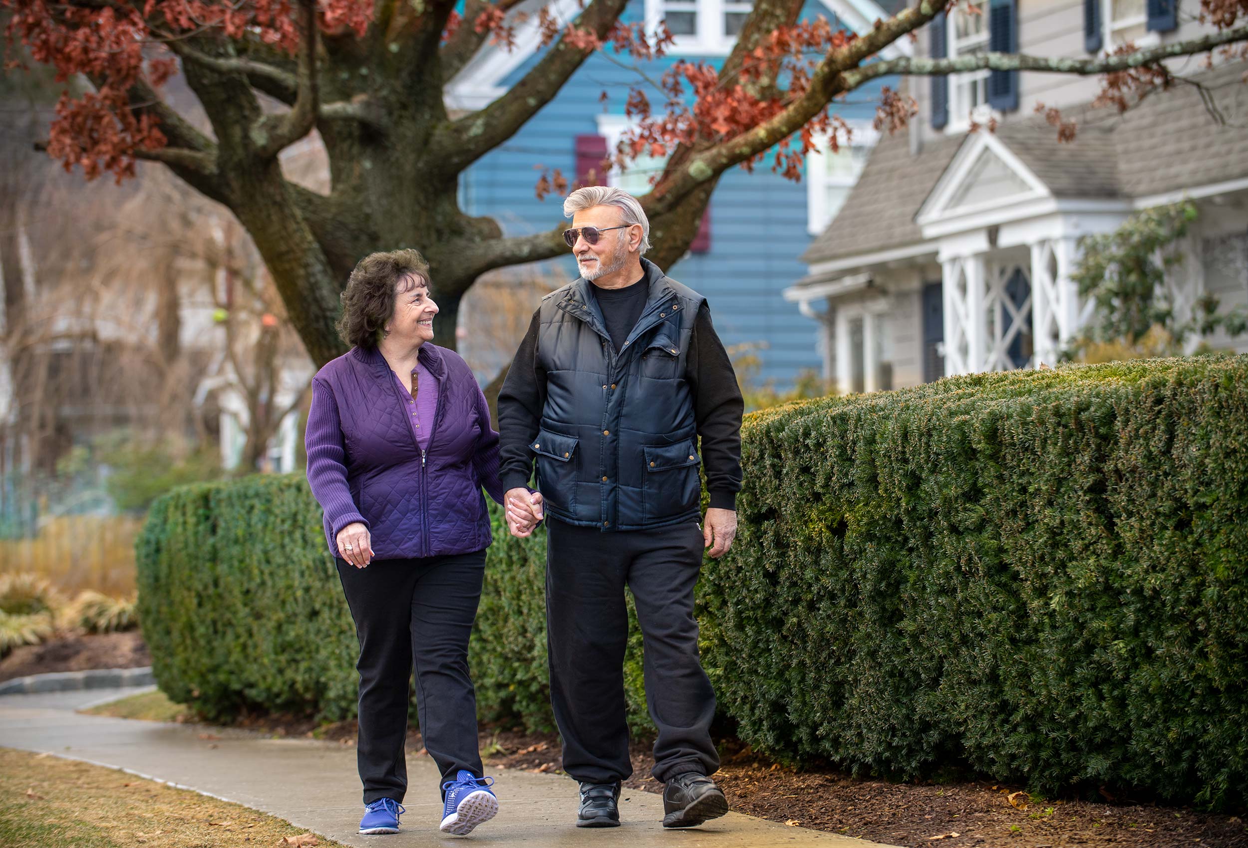 Senior citizens walk on sidewalk in suburban neighborhood
