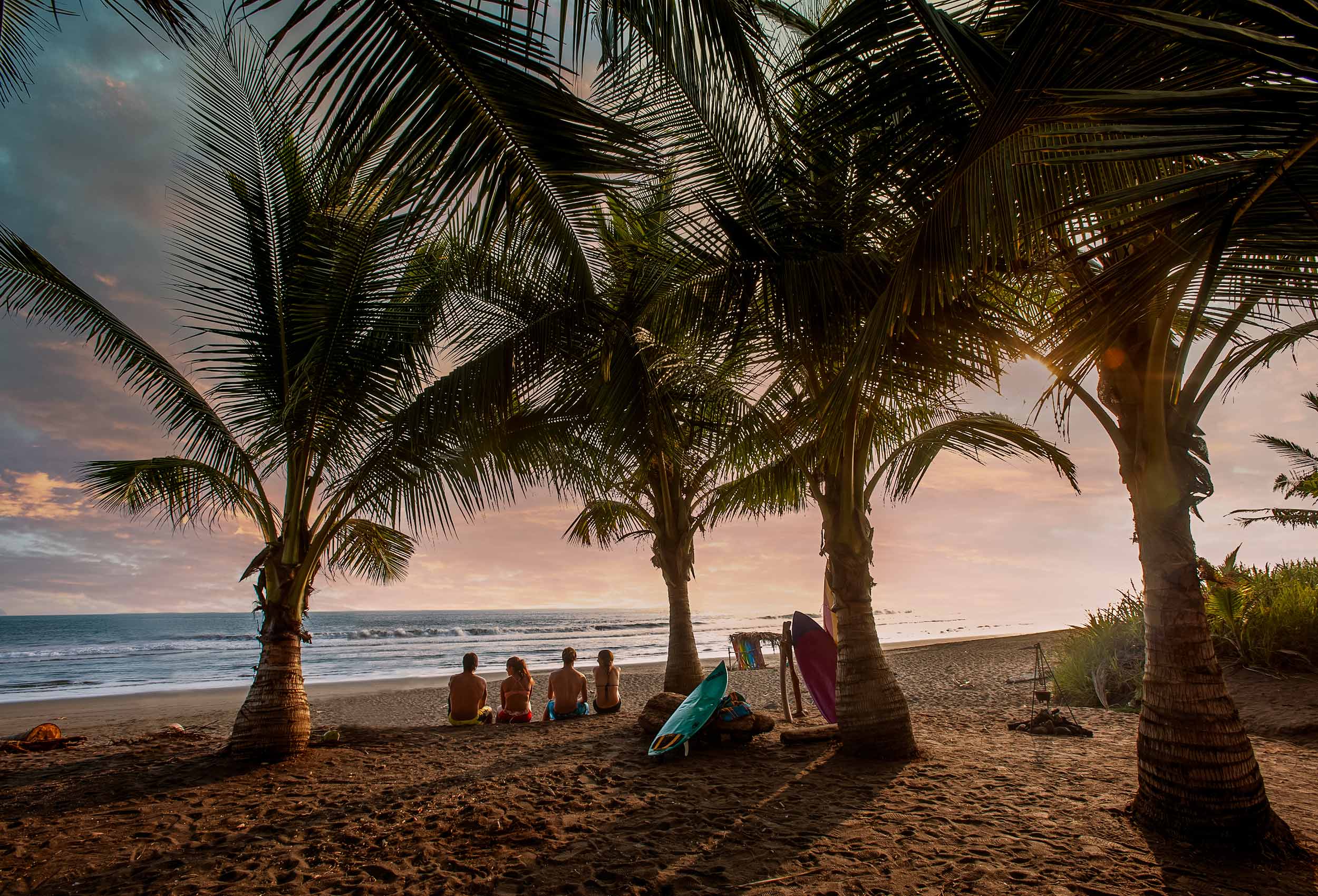 Surfers sit on beach in Costa Rica at sunset for Coppertone Embrace the Sun advertising campaign