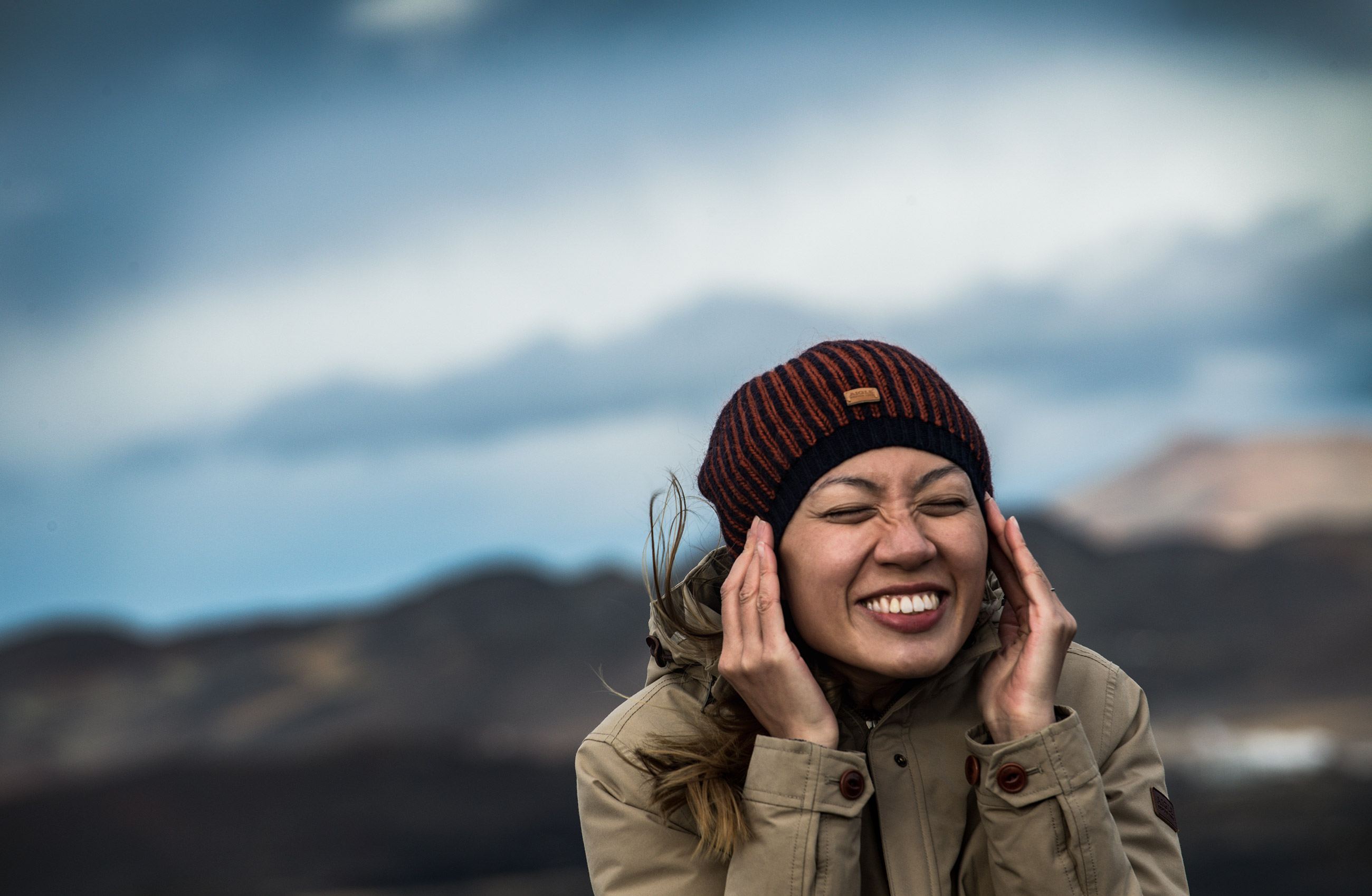 Girl holds hat in wind on volcano in Iceland