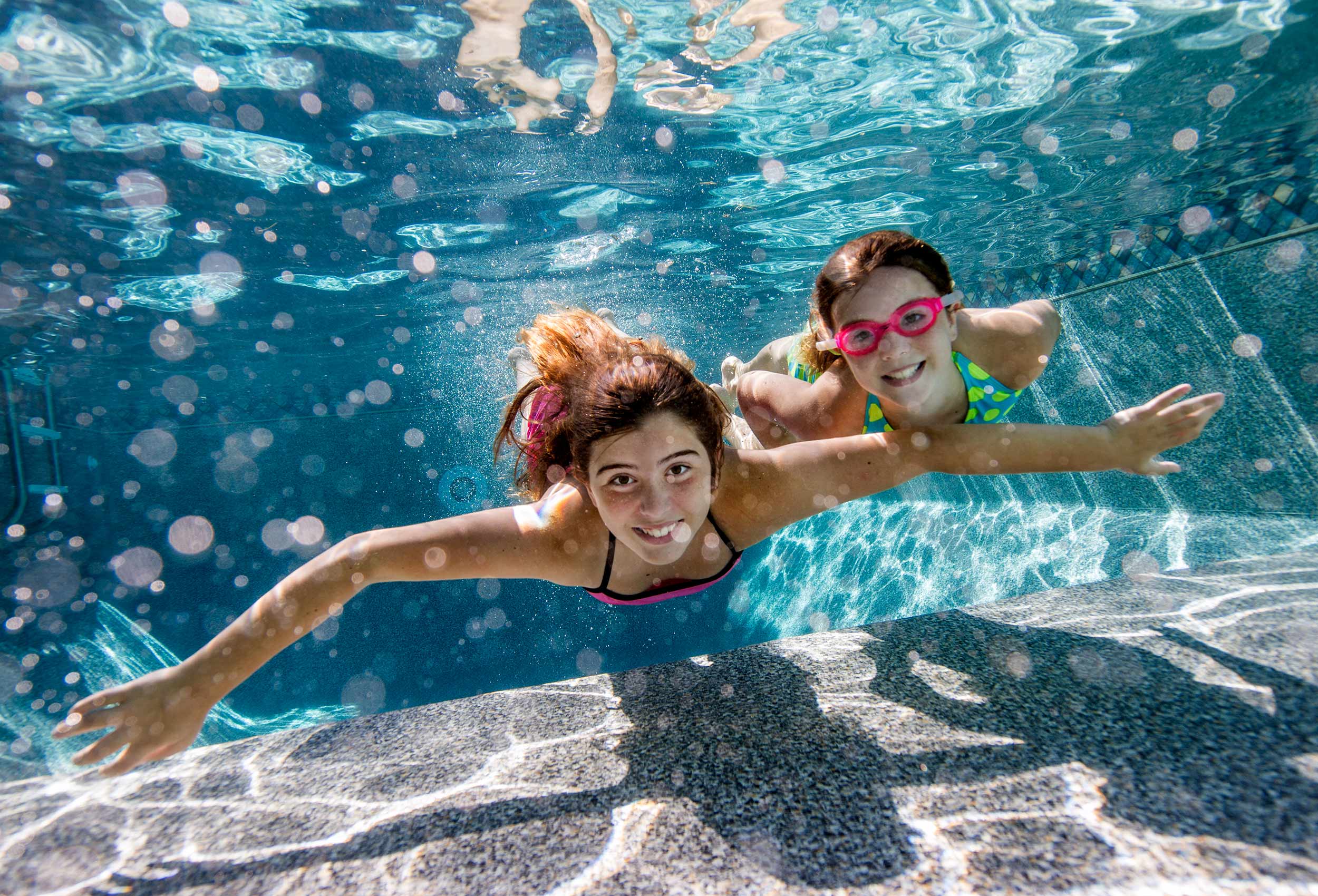Teen girls swim underwater in pool